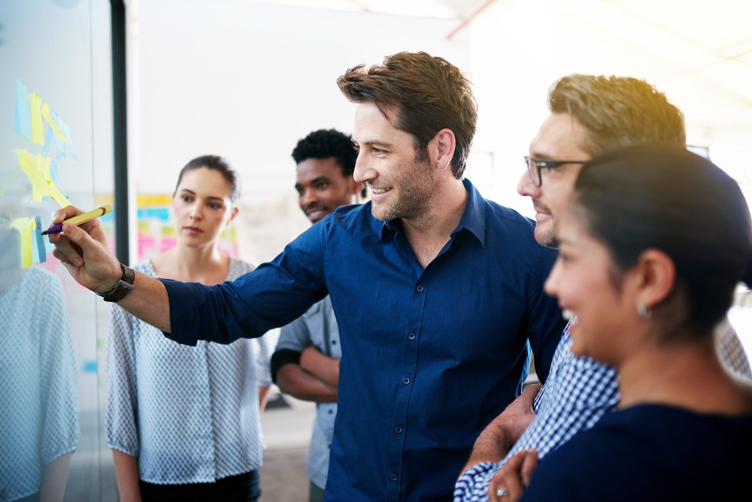 A team gathered in front of a whiteboard to make new branding guidelines