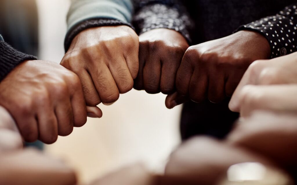 A group of sales professionals aligning their fists in motivation